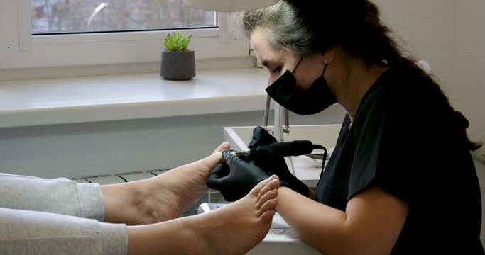  Beauty salon specialist doing French pedicure for client. Relaxation in beauty salon, nail care view of crop anonymous female masseuse massaging foot of customer while pedicure in modern beauty salon