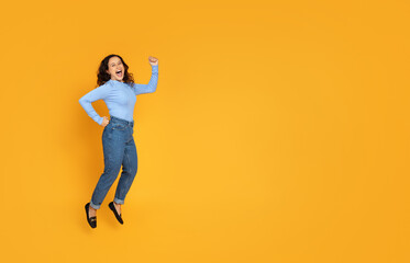 Fototapeta na wymiar Cheerful carefree young woman jumping on yellow