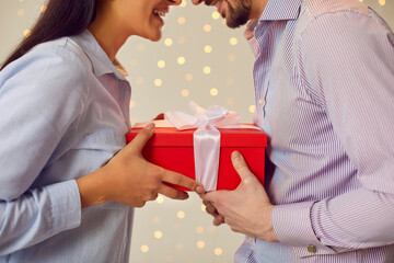 Cropped close up portrait of young happy couple man and woman holding red present gift box...