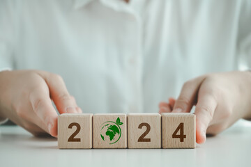 2024 ESG, Sustainable business or green business background. Environmental, social and governance in sustainability and ethical business concept. Hand holding wooden block number 2024 with world icon.