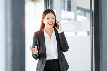 Smiling businesswoman using her phone in the office, smiling while communicating with her office colleagues