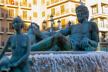 fountain with water in European city center with statues and faces