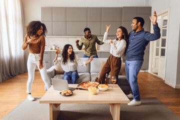 Multiracial group of friends students dancing enjoying weekend party indoor