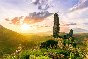 beautiful medieval castle ruins on mountain during nice sunset or sunrise with highland landscape...
