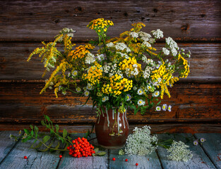 A bouquet of wildflowers and a branch of rowan with a bunch of red berries.