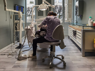 Dentista concentrada a tratar uma paciente no seu consultório - obrazy, fototapety, plakaty