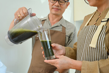 Middle age couple preparing healthy smoothie in kitchen. Healthy lifestyle and dieting concept