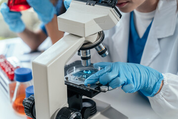 Team of biochemical research scientists working with a microscope for vaccine development in pharmaceutical research labeling.