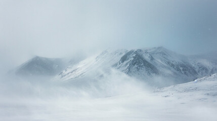 A blizzard engulfing a mountain range with snow and wind creating a whiteout condition.