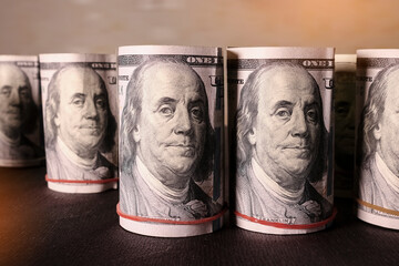 Rolled dollar bills stand in a row on a dark background. Finance and economics concept. Selective...