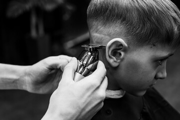 Black and white photo. Cute emotional fair-haired smiling boy with blue eyes at the barber shop....