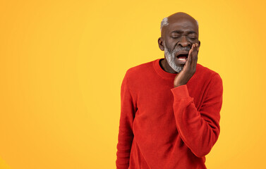Senior Black man with a white beard touching his cheek in pain, possibly having a toothache
