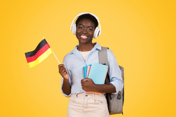 Happy teen african american woman student in wireless headphones, with books, flag of Germany