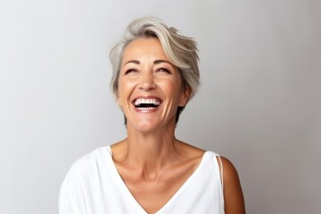 Portrait of a happy senior woman laughing against grey background with copy space