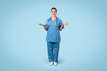 Happy woman nurse with open hands in blue scrubs