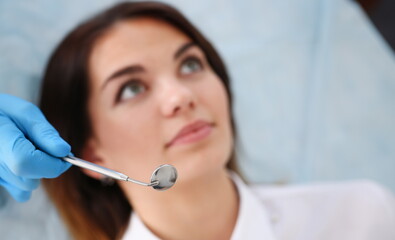 A woman at the reception of a male dentist examining teeth and oral cavity