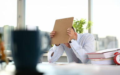 A man experiences stress and a headache in the workplace experiences negative emotions from paper...