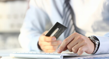 Fototapeta premium Male arms hold credit card press buttons making transfer closeup. Anti-fraud financial security when entering client discount program number or filling personal credential password login to account