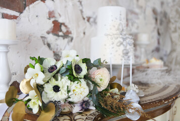 Fototapeta na wymiar Wedding cake with silver decoration and wedding bouquet with ranunculus
