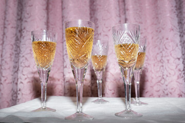 Five crystal glasses with champagne on a curtain background, nineties style concept