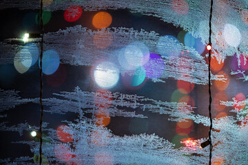 Frozen glass background with colored garland and bokeh, template for designer