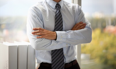 Male hands in suit crossed on chest closeup background. White collar dress code modern office...