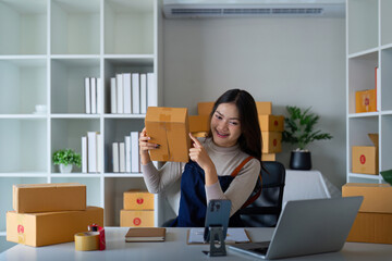 Women asian selling online at home with box. Selling online with box to accept order from customer. Live stream selling online. woman working smartphone and laptop at home