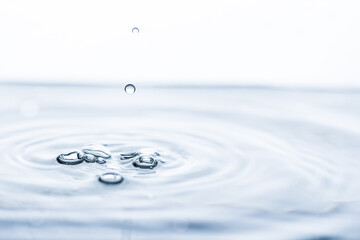 Captivating water drop creating intriguing shapes, movement, bubbles, and splashes on a white...