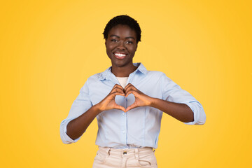 A black woman student creating a heart sign with her hands