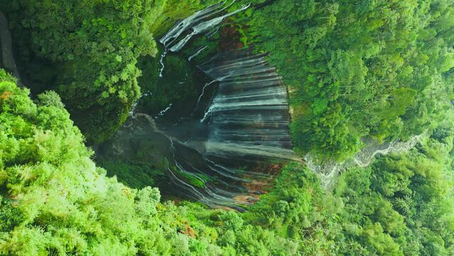 Aerial view powerful Tumpak Sewu waterfall located in Lumajang, East Java, Indonesia. Vertical drone video.