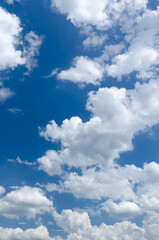 Obraz premium Fluffy white cumulus clouds in a blue sky on a beautiful day, natural soft background with copy space for text