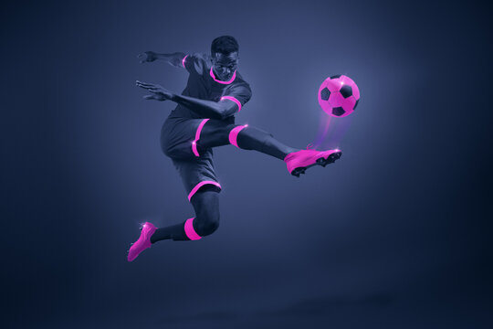 African young man, soccer player in mid-kick with selective purple coloring, illustrating movement and focus. Dynamic image of athlete during championship. Poster for sport events, game