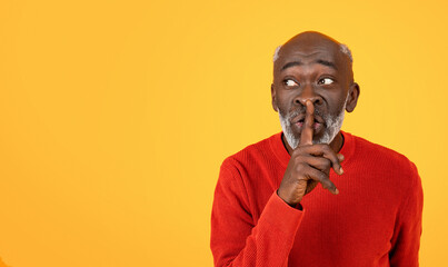 Secretive senior Black man with a white beard placing a finger to his lips in a shushing gesture - Powered by Adobe