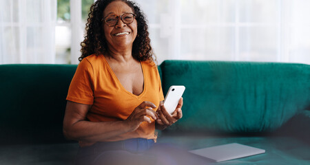 Mature woman enjoying retirement at home, using a smartphone to stay connected