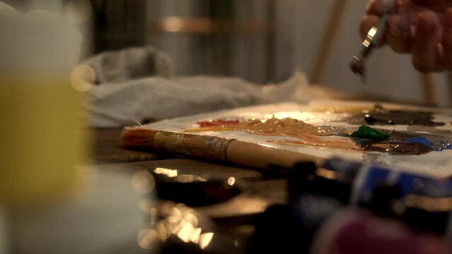 Closeup woman female hand artist painter paints draws creating new art work on canvas in workshop lesson of painting enjoying process of drawing creating picture using brush applying oil paint palette