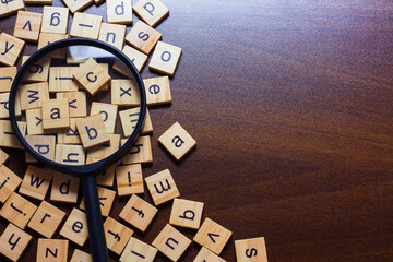 English letters scattered on the table. magnifying glass on the newspaper