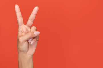 Isolated hand on an orange background with the index and middle fingers extended