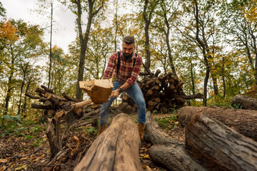 A young Caucasian lumberjack energetically chopping wood with an axe in the forest.