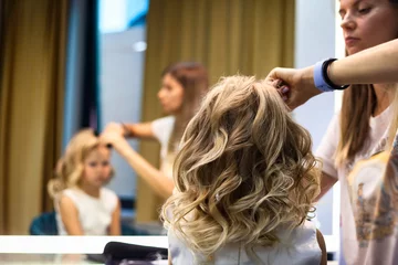 Foto auf Acrylglas Hair salon, barber lady make hairdo with comb for girl in barber shop at mirror, haircare. Hairdresser combing curly hair kid in barbershop. Customer service at hair salon concept. Copy ad text space © Alex Vog