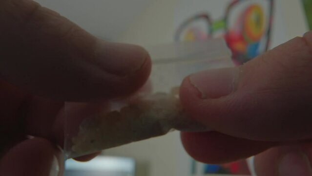 MDMA crystals bag explored by hands. Drug known as Molly or Ecstasy or methylenedioxymethamphetamine.
