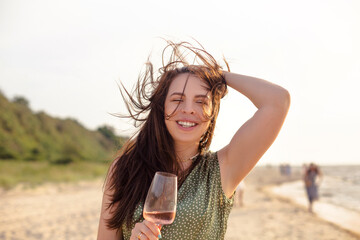 Happy adult woman with wine resting on beach