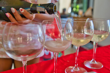 Woman hand pouring prosecco sparkling wine in glasses during festive season