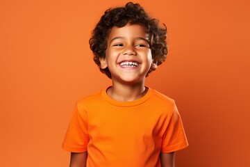 a professional portrait studio photo of a cute mexican boy child model with perfect clean teeth laughing and smiling. isolated on orange background. for ads and web design