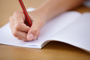 School, notebook and hand of child writing on desk with pencil, notes and learning for education....
