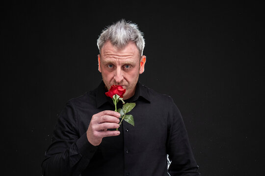 Hombre elegante oliendo una rosa roja
