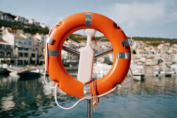 Orange lifebuoy hangs on a metal stand with a lock on the dock