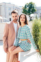 Beautiful fashion woman and her handsome elegant boyfriend in beige suit. Sexy brunette model in summer clothes. Fashionable smiling couple posing in street Europe. Brutal man and female outdoors