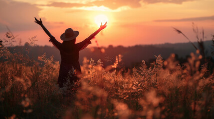 Silhouette photo of one woman standing in outdoor grasses field raising two hands in the air...