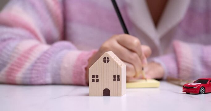 Detail of female hand carrying out financial planning for investment in housing and transport