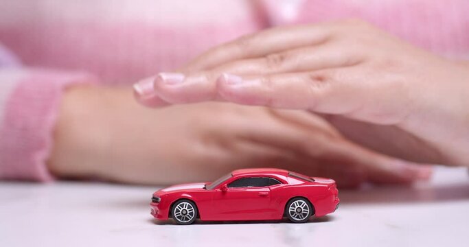 Hand hovering over a red toy sportscar, manifesting the desire to own a new vehicle through a car bank loan.